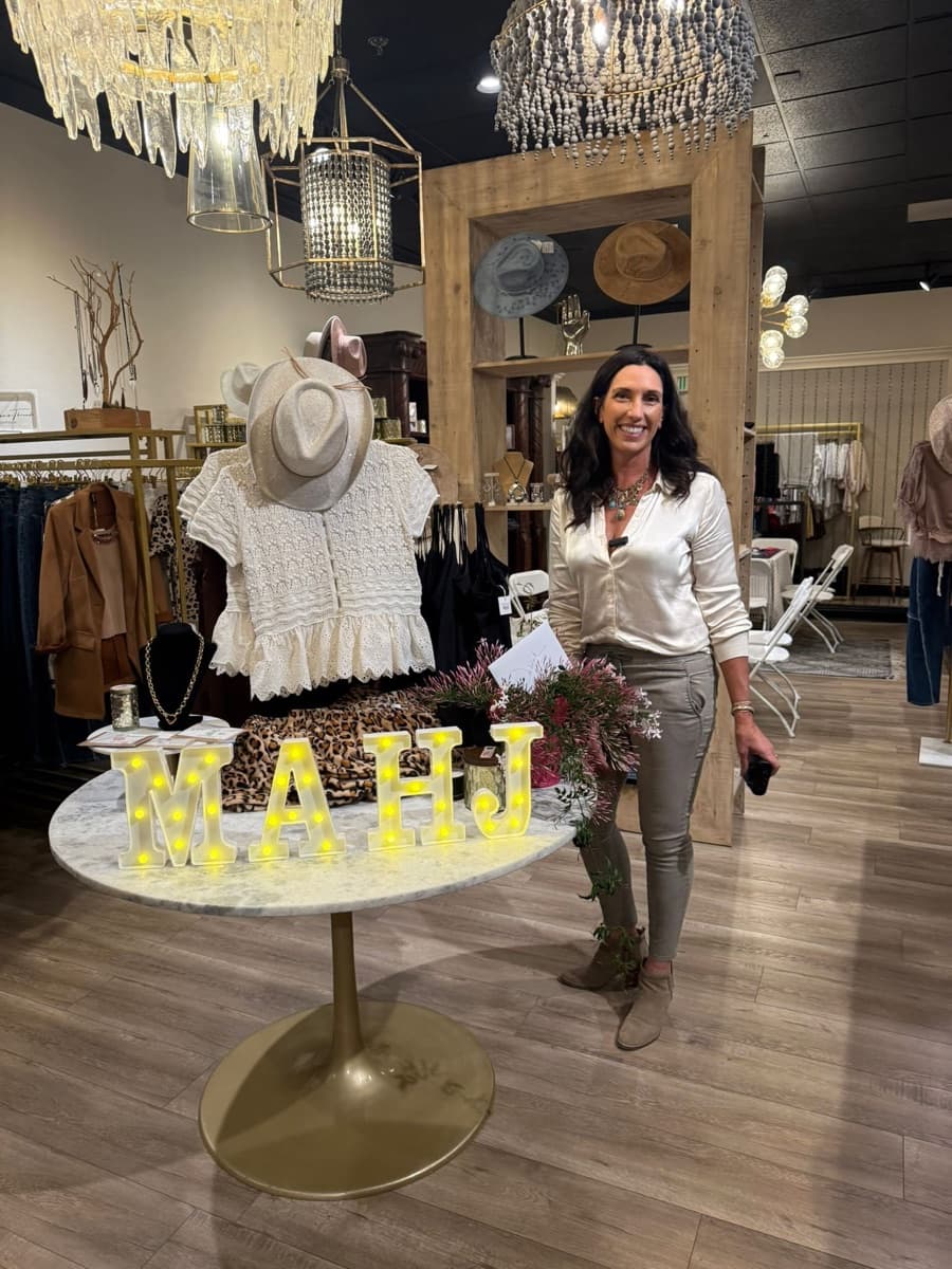 Deborah Najm, founder of Starlit Creative, at Anissa's Threadz Boutique with the MAHJ marquee